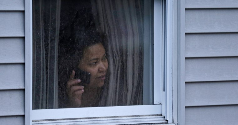 A woman looks out a window at her home as police start to search an apartment building in Watertown on April 19.