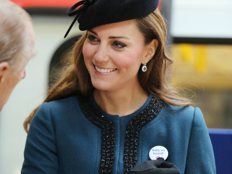 Britain's Catherine, Duchess of Cambridge holds a "Baby on board!" badge given to her during her visit to Baker Street underground station in London M...