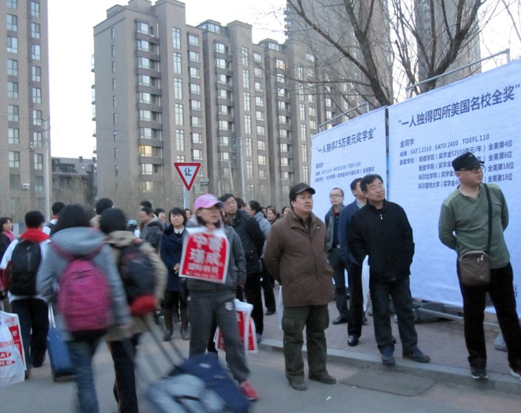 Parents wait to pick up their children at Yucai Northeast High School in Shenyang, China -- the school that Lu Lingzi, the Chinese victim of the Boston Marathon bombing attended. The parents stand next to billboards listing the names of top American schools where alumni won scholarships.