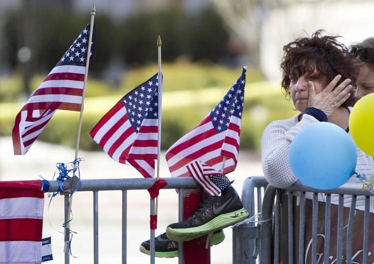 A woman wipes a tear at a memorial for the victims of the Boston Marathon bombing on Boylston Street near the race finish line, on April 22, in Boston, Mass. At 2:50 p.m., exactly one week after the bombings, many bowed their heads and cried at the makeshift memorial on Boylston Street, three blocks from the site of the explosions, where bouquets of flowers, handwritten messages, and used running shoes were piled on the sidewalk.