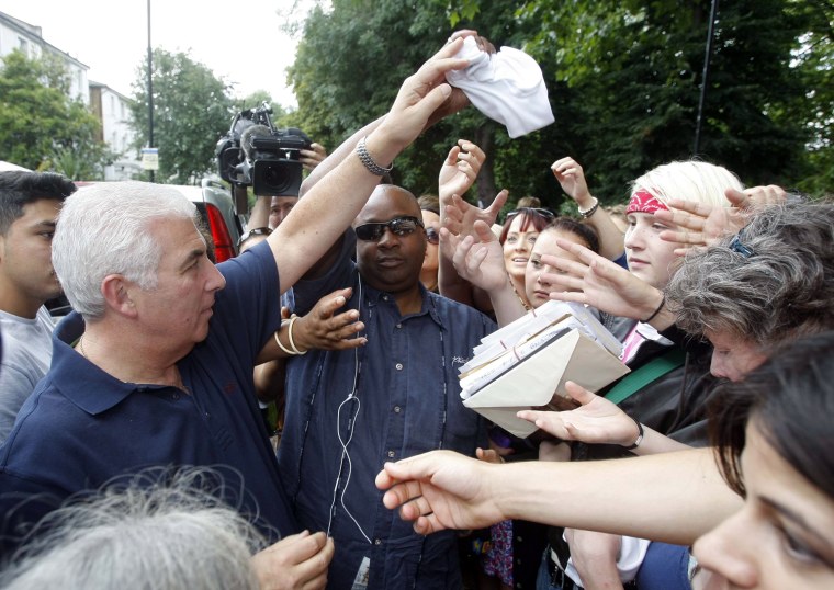 Mitch Winehouse gives out some of Amy Winehouse's T-shirts to well wishers outside the late singer's house in London.