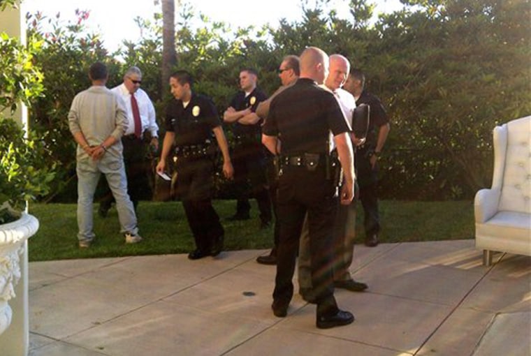 In a photo released by Paris Hilton, Los Angeles police detain a man, left, at the home of the celebrity heiress.