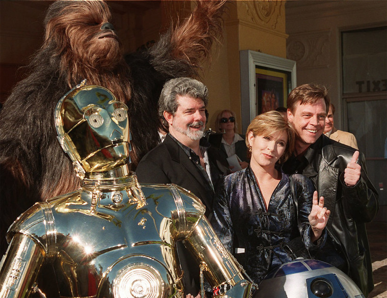 Carrie Fisher with George Lucas, Mark Hamill, Chewbacca, C-3PO and R2-D2 at a Star Wars event in 1997.