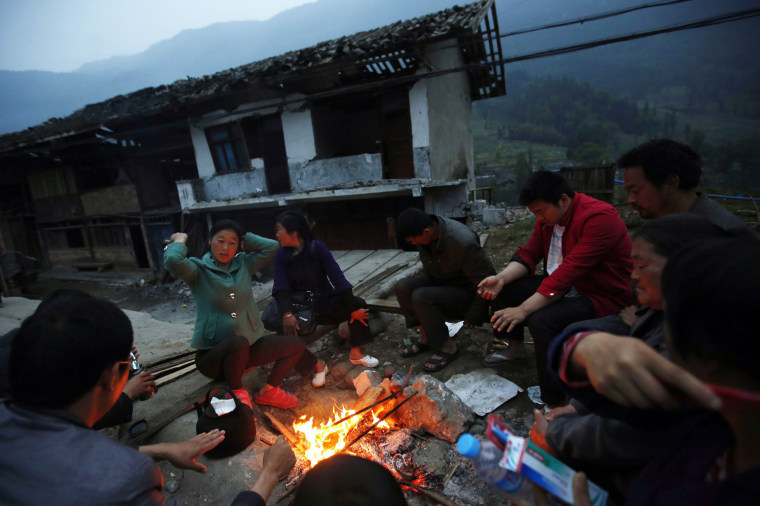 Residents gather around a fire outside damaged homes in Taiping town, Lushan County, Sichuan Province, China, on April 23.