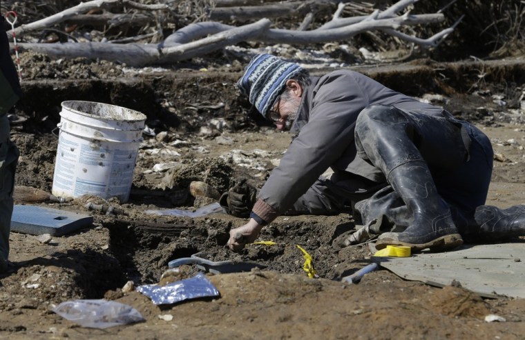 Archaeologist Thomas Klatka works on a grave site being claimed by the sea on the north end of Tangier Island, Va., on April 3. Climate change is accelerating what experts say will be increasing flooding along the bay and the foreseeable demise of Tangier.