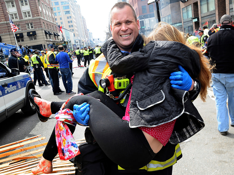 In this Monday, April 15, 2013 photo, Boston Firefighter James Plourde carries an injured girl away from the scene after a bombing near the finish lin...