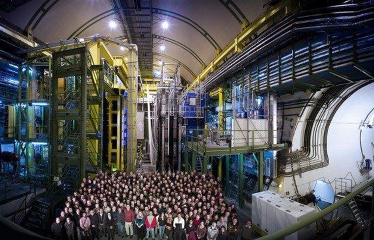 The LHCb team stands in front of its experiment, the LHCb detector, at the Large Hadron Collider in Geneva.