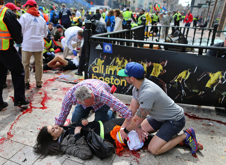 Bystanders help Sydney Corcoran, a 17-year-old senior at Lowell High School, at the scene of the first explosion on Boylston Street near the finish line of the 117th Boston Marathon.