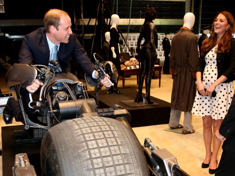 Catherine, Duchess of Cambridge (R) watches as Prince William, Duke of Cambridge sits on the 'Batpod'  during their visit at the Warner Brother's stud...