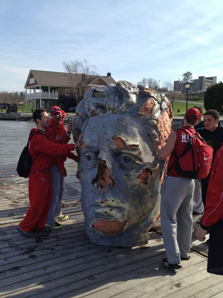 Members of the Marist college crew team stand by a giant foam head found floating in the Hudson River in Poughkeepsie, N.Y., on Monday, April 22.
