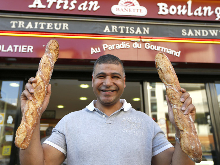 Parisian baker Ridha Khadher, winner of the Best Baguette of Paris 2013 award, holds his baguettes, French bread, as he poses in front of his bakery a...
