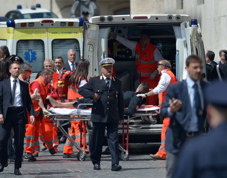 An Italian policeman is carried away by paramedics after two policemen were wounded in a shooting outside the Italian prime minister's offices as the country's new ministers were being sworn in on Sunday.