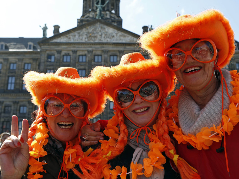 Visitors from Sydney, Australia wearing the Dutch national colors pose for photographers outside the Royal Palace in downtown Amsterdam, Netherlands M...