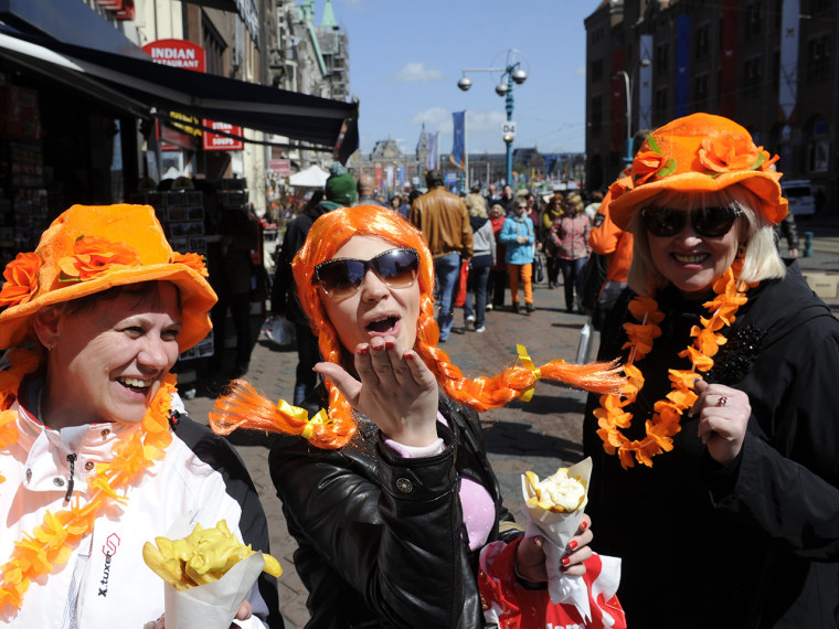 epa03681162 Tourists wear funny 'Oranje' (orange) headgear in anticipation of the upcoming investiture of the country's new King, in Amsterdam, The Ne...