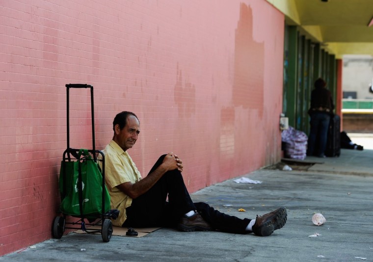 Juan Morena sits on a Los Angeles, Calif., sidewalk as he waits for the St. Francis Center soup kitchen to open on Sept. 13.