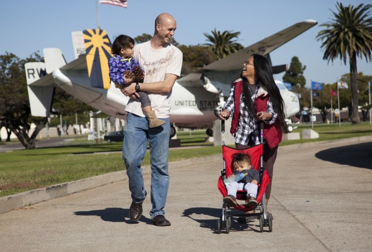 Jason Ruediger carries his 2-year-old daughter, Aureus, while his wife pushes their 1-year-old son, Crichton, on the Naval Air Station North Island in Coronado, Calif.