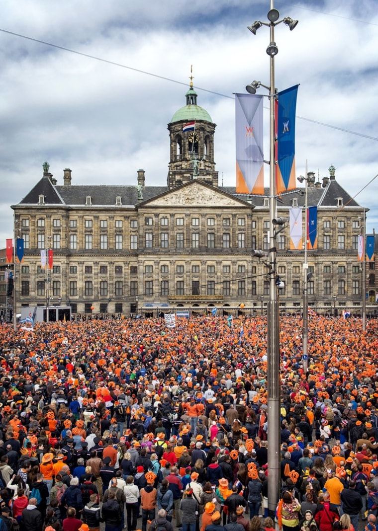 People, most of them wearing orange T-shirts, hats or plastic crowns, gather in Dam Square on Tuesday to celebrate their new king. Orange is The Netherlands' royal color.