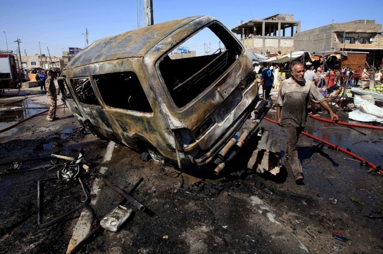 People and security forces inspect the site of a car bomb explosion in Basra, 340 miles southeast of Baghdad, Iraq, on July 29. A wave of over a dozen car bombings hit central and southern Iraq during morning rush hour on Monday, officials said, killing scores in the latest coordinated attack by insurgents determined to undermine the government.