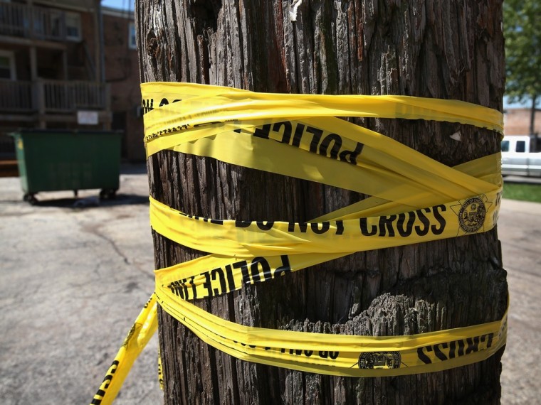 Crime scene tape is wrapped around a power pole near the location where a 20-year-old man died from a gunshot wound to the head and a 15-year-old boy was shot and wounded during weekend violence on May 13, 2013 in Chicago