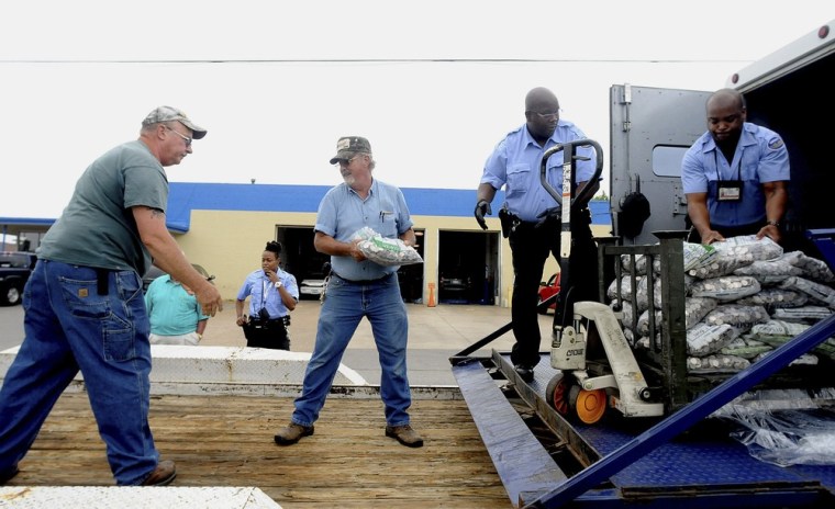 Workers unload dozens of bags full of coins from a Brinks Security truck on Wednesday. Four tons of quarters were delivered by Roger Herrin, who was paying off a portion of a court-ordered legal settlement — related to a car accident in which his teenage son died — with quarters packed into dozens of bags.