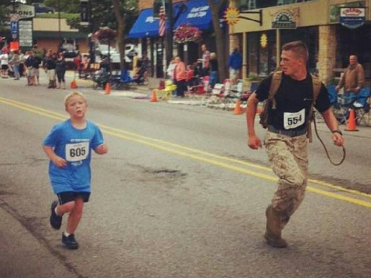 Lance Corporal Myles Kerr helps 9-year-old Boden Fuchs across the finish line.