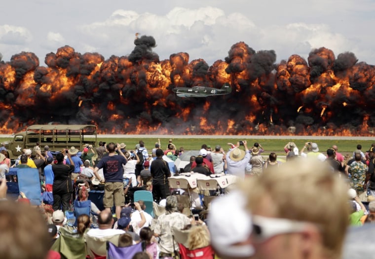 A World War II American plane flies in front of a wall of fire as it takes part in a re-enactment of the attack on Pearl Harbor during an afternoon air show at the EAA AirVenture at Wittman Regional Airport in Oshkosh, Wisconsin August 3.