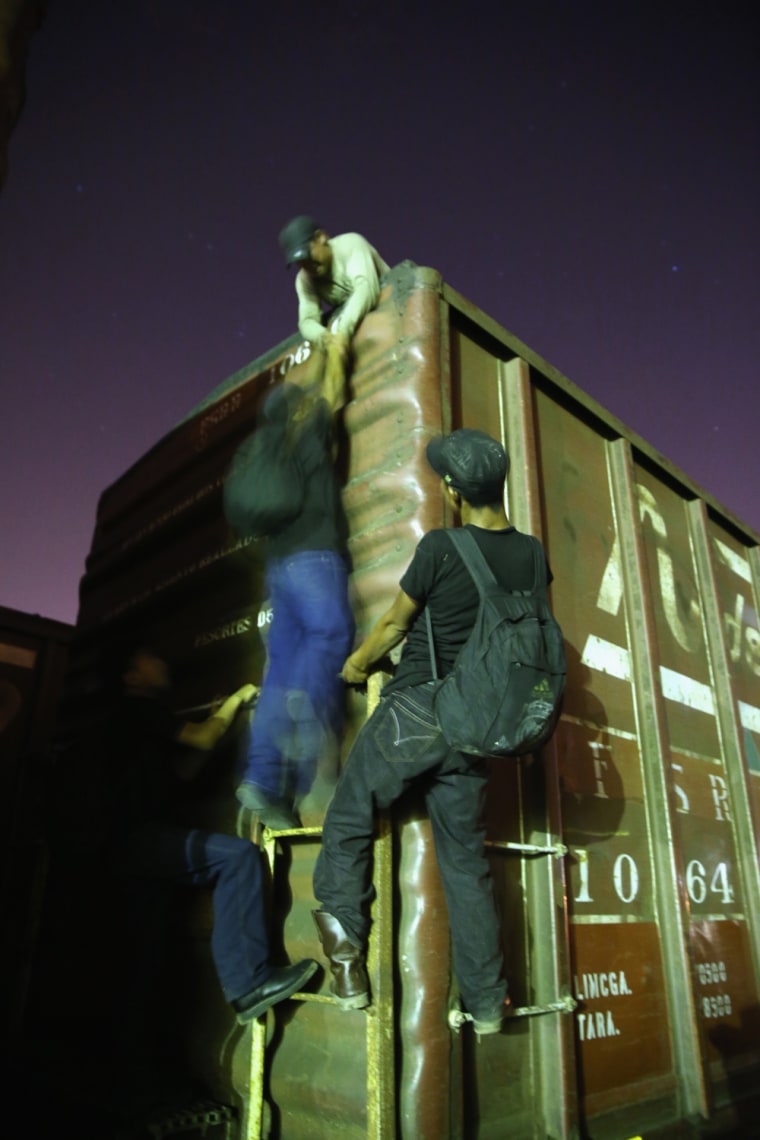 Central American immigrants climb atop a freight train headed north.