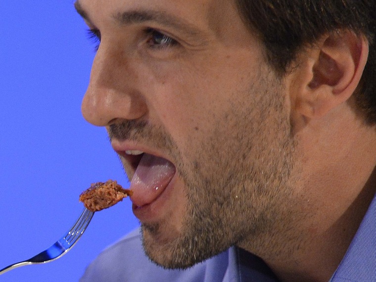 Josh Schonwald, a US-based food writer, tastes the world's first lab-grown beef burger during a launch event in west London, August 5, 2013. The in-vi...