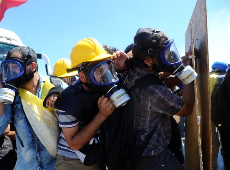 Turkish protesters wearing gas masks protect themselves behind wooden boards at a police barricade near a courthouse in Silivri, near Istanbul, where prosecutors delivered their final arguments in the case against 275 people accused of plotting to overturn the Islamic-leaning government.