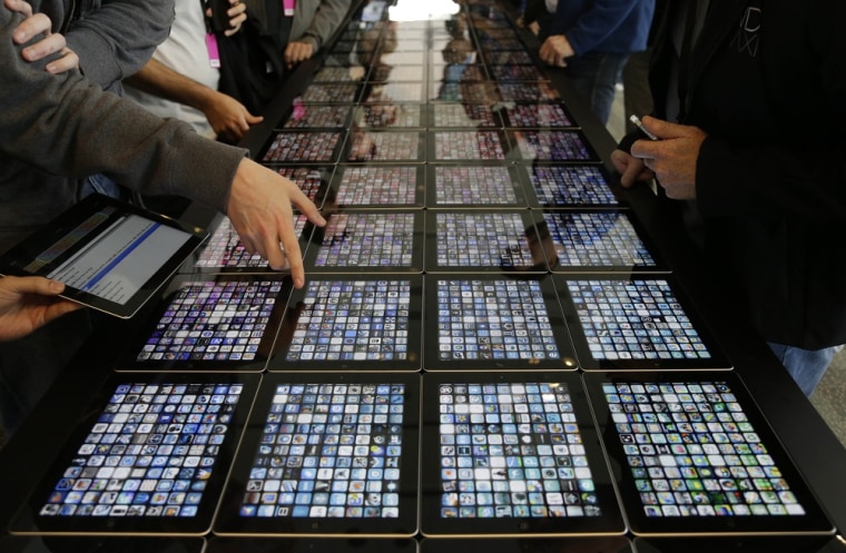 Developers look over new apps being displayed on iPads at the Apple Worldwide Developers Conference Monday, June 10, 2013 in San Francisco. (AP Photo/...