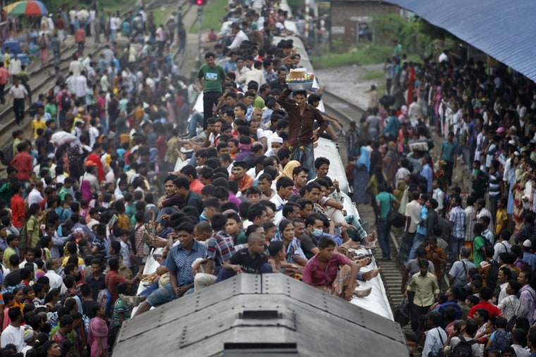 Passengers sit on the top of an overcrowded train as it approaches a railway station in Dhaka on Aug. 8. Millions of residents in Dhaka are traveling home from the capital city to celebrate the Muslim Eid al-Fitr holiday.