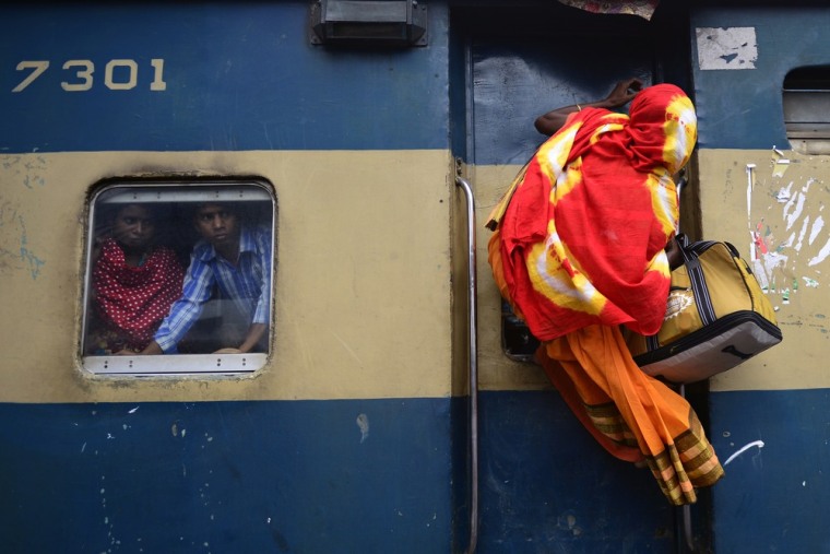 A Bangladeshi woman climbs on top of a train as passengers look on from a compartment window as they rush home to their respective villages to be with their families ahead of the Muslim festival of Eid al-Fitr, in Dhaka on Aug. 8.