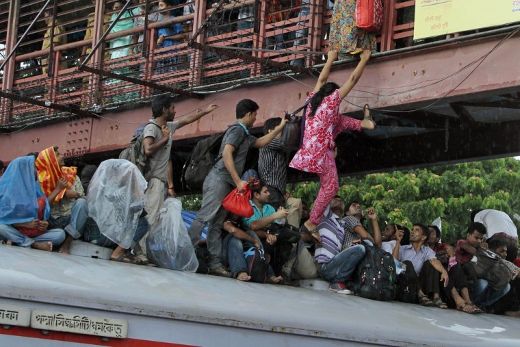 A Bangladeshi woman tries to jump onto an overcrowded train from a bridge to travel home for Eid al-Fitr in Dhaka, Bangladesh.