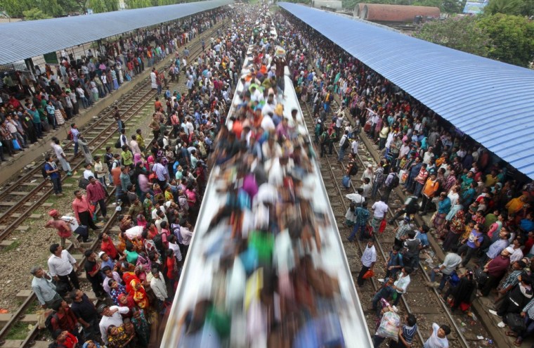 Bangladeshi Muslims travel on the roof of a train to head home ahead of Eid al-Fitr as others wait at a railway station in Dhaka, Bangladesh, on Aug. 8.