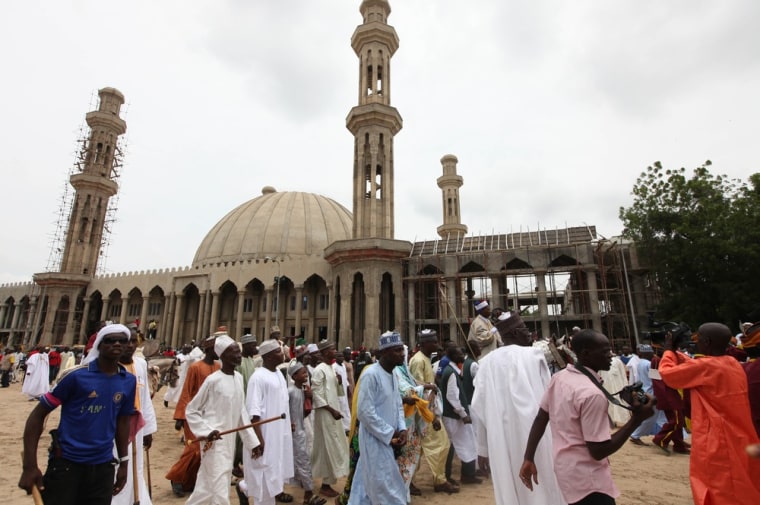 In this photo taken Thursday, Aug. 8, 2013, Nigerian Muslims walk past an uncompleted mosque in Maiduguri, Nigeria. Suspected Islamic militants wearing army fatigues gunned down 44 people praying at a mosque in northeast Nigeria, while another 12 civilians died in an apparently simultaneous attack, security agents said Monday Aug. 12, 2013.
