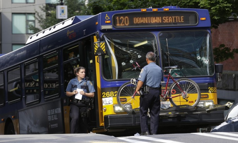 Seattle Police officers stand next to a King Co. Metro bus with multiple bullet holes in its windshield, after a Metro bus driver was shot on Monday.