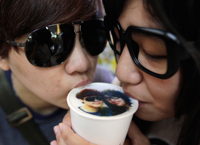 A couple drinks a latte with their picture printed on top of the milk foam at a Family Mart in Taipei on Aug. 13, 2013.