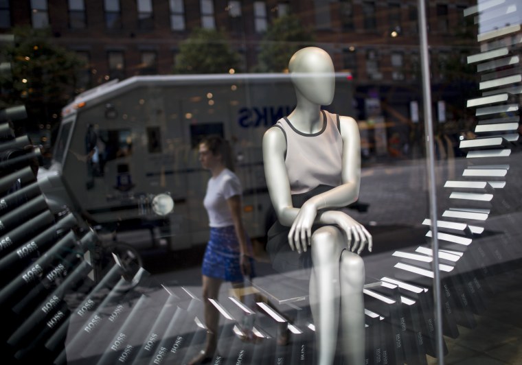 A shopper walks past a store window display in New York, U.S., on Wednesday, July 24, 2013. The U.S. Conference Board is scheduled to release consumer...