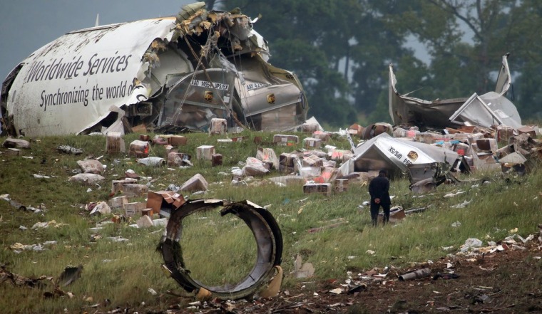 An investigator looks through debris of a UPS A300 cargo plane after it crashed on approach at Birmingham-Shuttlesworth International Airport, Wednesday, Aug. 14, 2013 in Birmingham, Ala. The two pilots aboard were killed.