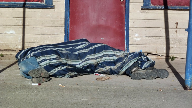 Homeless people cover themselves with a blanket on a street in Whiteclay, Neb., on Aug. 9. Many tribal members live on the tiny town's barren streets to avoid arrest on the nearby reservation for being drunk.