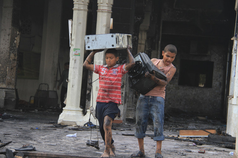 Egyptian children carry computer equipment from the burned remains of the mosque.
