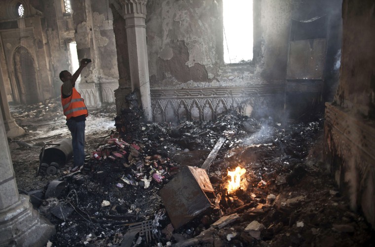 An Egyptian man stands near a burning fire as he takes a picture of the damage at Rabaah al-Adawiya Mosque.