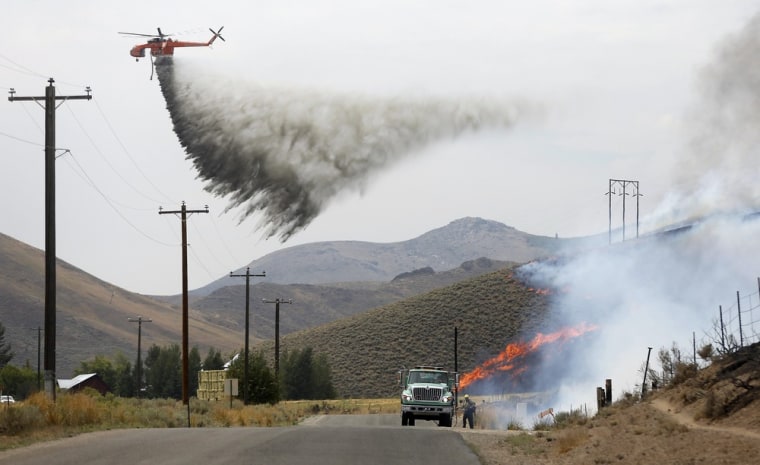 A tanker helicopter drops water as a firefighter works to douse a hot spot at the Beaver Creek wildfire outside Hailey, Idaho, on Saturday.