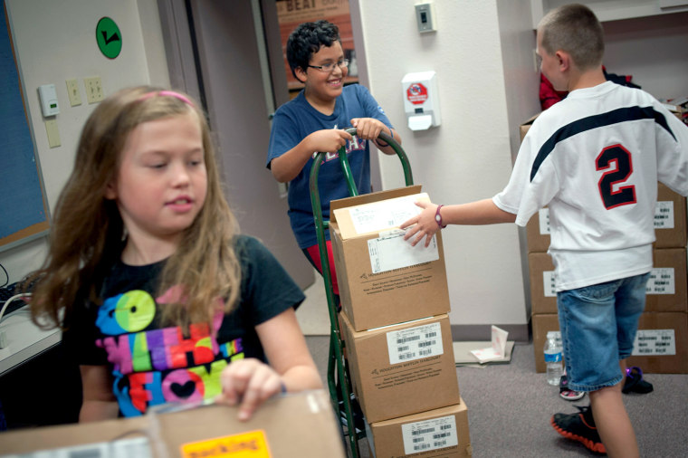 West Elementary School students, left to right, Lauren Scott, Noah Grmela, and Redon Dobecka, help place bar codes in new books at the school, on Aug. 16.