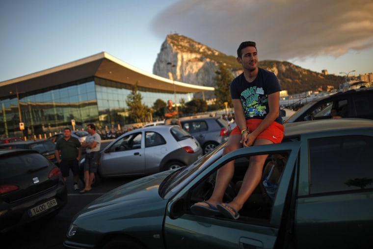 A driver sits on the roof of his car as he and other drivers wait in line to enter to Spain at its border with the British territory of Gibraltar on August 9.