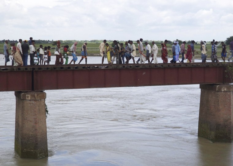 Indian villagers walk through a railway bridge after a train ran over a group of Hindu pilgrims at a crowded station in Dhamara Ghat, India, Monday.