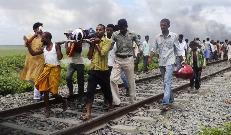 Indian villagers carry an injured person after a train ran over a group of Hindu pilgrims at a crowded station in Dhamara Ghat, India, Monday.