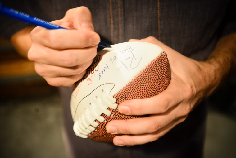 Paul Charchian, local radio host and head of the Fantasy Sports Trade Association, signs a football for a fantasy football fan at the Pourhouse restau...