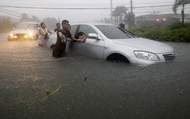 Bystanders push a car in floodwaters brought by the monsoon rain, intensified by tropical storm Trami, in Pasay city, metro Manila. More than 94,000 people were affected by the floods and heavy rain in Manila and northern provinces, including some 12,000 residents forced to flee their homes.
