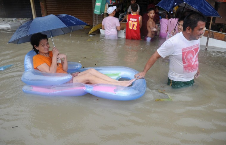 A man pulls his wife in an inflatable boat as they buy food at a submerged market in Cavite, southwest of Manila.